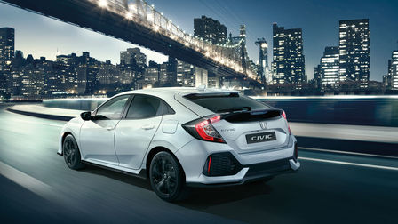 Honda Civic Sport Line in 3/4-Heckansicht bei der Fahrt durch die Stadt.