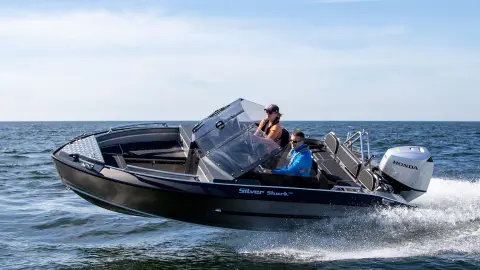 Ehepaar auf einem silbernen Haiboot mit Honda-Motor. 