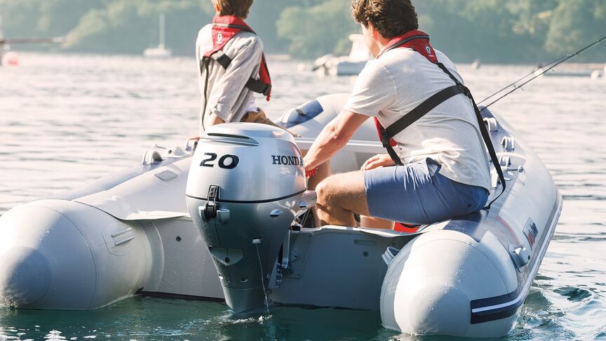 Mann auf einem Boot mit einem BF15-Motor an der Küste. 