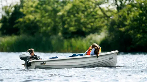 Zwei Personen liegen in einem Boot auf dem Wasser mit einem Honda-Motor.