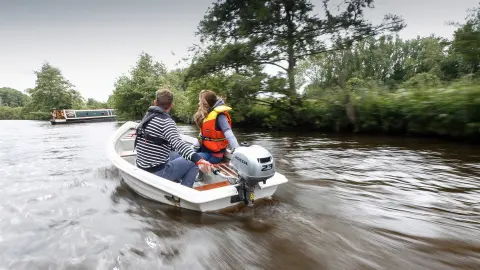 Zwei Personen in einem Boot, das den BF2.3-Motor verwendet, neben einem Kanalboot.