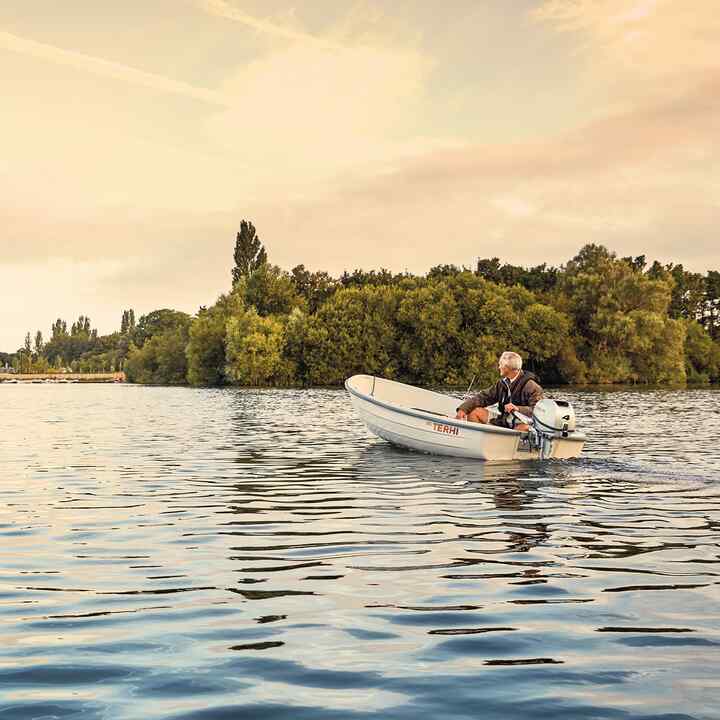 Mann auf einem Boot mit Honda Motor auf einem See. 