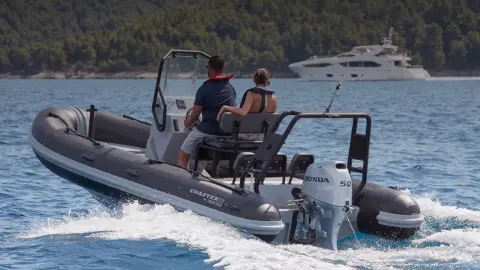 Paar auf einem Highfield-Boot mit BF50-Motor in maritimer Umgebung, Heckansicht.