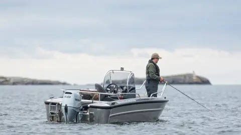 Ein Herr angelt auf einem Boot mit Honda BF60-Motor.