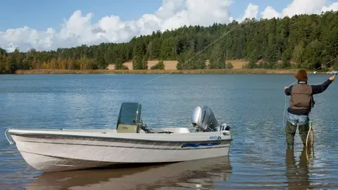 Model beim Angeln auf einem See mit Boot in der Nähe, das mit einem BF8-10-Motor ausgestattet ist.