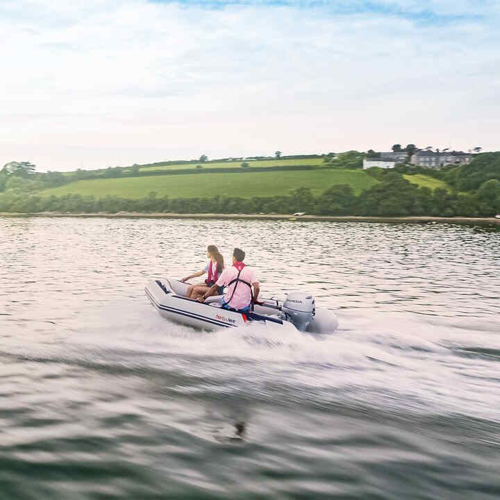 Paar auf einem Honwave-Boot mit Honda BF-Motor auf einem See. 