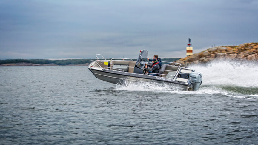 Model, das ein Boot mit BF80-100-Motor über das Meer steuert.