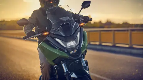 NC750X-Motorrad mit Model auf der Straße, Frontansicht.